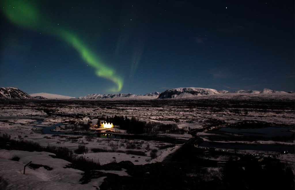Þingvellir at night, with northern lights and volcanoes in the background